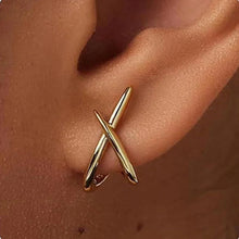 Gold cross stud earrings dainty minimalist design flat lay view.