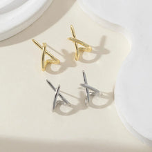 Gold cross stud earrings worn on ear showing clean polished look.