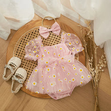 Daisy print baby romper worn by a baby girl